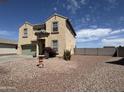 A two-story home with a neutral stucco exterior, complemented by desert landscaping for a low-maintenance front yard at 703 N Redwood Ln, Buckeye, AZ 85326