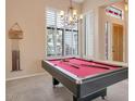 Game room with a pool table, chandelier, and plantation shutters with natural light at 10907 E Bella Vista Dr, Scottsdale, AZ 85259