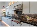 Modern kitchen showcases black marble countertops, sleek stainless steel appliances, white cabinetry, and wood flooring at 14141 E Highland Ave, Fountain Hills, AZ 85268