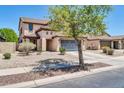 View of a two-story home showcasing a tile roof, attached two-car garage, and desert landscaping at 14200 W Larkspur Dr, Surprise, AZ 85379
