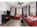 Inviting living room featuring bright natural light, wood floors, red sofas, and a ceiling fan at 14575 W Mountain View Blvd # 11220, Surprise, AZ 85374