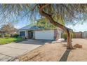 View of the two-story home with solar panels, two-car garage, and spacious front yard with mature tree at 17819 N 46Th Dr, Glendale, AZ 85308