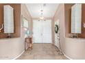 View of a tiled foyer with a mirror, table, lamps and a decorative front door at 18482 W Marconi Ave, Surprise, AZ 85388