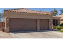 Inviting front view featuring a three car garage with brick accents, large driveway, and meticulously maintained landscaping at 20420 N 93Rd Dr, Peoria, AZ 85382