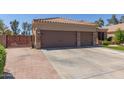 Inviting front view featuring a three car garage with brick accents, large driveway, and meticulously maintained landscaping at 20420 N 93Rd Dr, Peoria, AZ 85382