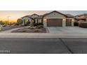 Single-story home with desert landscaping, a paved walkway, and a well-lit two-car garage at 20506 N 271St Ave, Buckeye, AZ 85396
