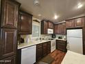 Well-lit kitchen with white appliances, dark cabinets, and laminate countertops at 650 N Hawes Rd # 4123, Mesa, AZ 85207