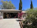 View of the house garage featuring an open door and exterior trees and shrubbery at 6512 E Portia Cir, Mesa, AZ 85215