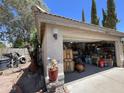 Garage with open door showing storage items, plus exterior landscaping with potted plants at 6512 E Portia Cir, Mesa, AZ 85215