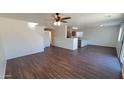 Spacious living area with modern ceiling fan, wood-look laminate floors, and bright, neutral walls at 10521 W Toronto Way, Tolleson, AZ 85353