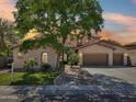 Charming two-story home with a three car garage, lush landscaping, and mature shade tree at sunset at 1360 S Camellia Ct, Chandler, AZ 85286