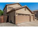 Side view of a 3-car garage with a private gated entrance on a paved driveway at 26249 N 68Th Ln, Peoria, AZ 85383