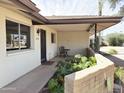 Covered front porch with an outdoor seating area, decorative brick surround, and lush green plants at 2749 S Rita Ln, Tempe, AZ 85282