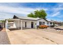 Charming single-story home with black and white trim and a covered carport, desert landscaping with blooming shrubs at 2914 W Marlette Ave, Phoenix, AZ 85017