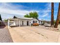 Charming single-story home with black and white trim and a covered carport, desert landscaping with blooming shrubs at 2914 W Marlette Ave, Phoenix, AZ 85017
