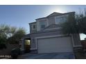 Two-story home featuring a two-car garage and a covered porch with stone accents. Landscaped with desert trees and bushes at 3402 N 300Th Dr, Buckeye, AZ 85396
