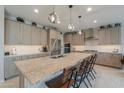 Spacious kitchen with an oversized granite island, stainless appliances, and modern lighting at 40725 W Hall Dr, Maricopa, AZ 85138