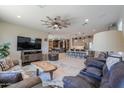 Open-concept living room with a ceiling fan and easy access to the kitchen and bar at 40725 W Hall Dr, Maricopa, AZ 85138