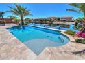 Gorgeous waterfront pool with travertine tile surround and lush tropical landscaping at 40725 W Hall Dr, Maricopa, AZ 85138