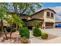 Exterior view of a two story home with a three car garage, desert landscaping and mature trees at 5910 W Blue Sky Dr, Phoenix, AZ 85083