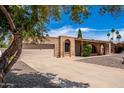 Brick single-story home with two-car garage, large driveway, desert landscaping, and tile roof at 6622 E Voltaire Ave, Scottsdale, AZ 85254