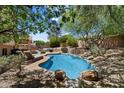 Beautiful backyard oasis with a freeform pool, lush landscaping, and lounge area for relaxation at 7438 E Glenn Moore Rd, Scottsdale, AZ 85255