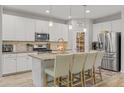 Bright kitchen featuring white cabinets, a stylish backsplash, stainless steel appliances, and a central island with bar seating at 7732 S 23Rd St, Phoenix, AZ 85042