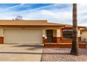 Single-story home with a two-car garage, desert landscaping, and a warm inviting entrance with brick accents at 8255 E Kiva Ave # 420, Mesa, AZ 85209