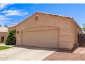 Beige home showing attached two car garage and a meticulously manicured lawn at 11411 W Dana Ln, Avondale, AZ 85392