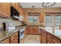 Well lit kitchen with stainless steel appliances, wooden cabinets, granite countertops and a large island at 3152 E San Pedro Ct, Gilbert, AZ 85234