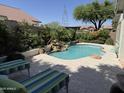 Beautiful backyard pool with rock waterfall feature, surrounded by mature landscaping and lounge chairs at 4223 E Wildcat Dr, Cave Creek, AZ 85331