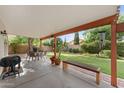 Covered patio includes an outdoor dining area, bench seating, and views of the landscaped backyard at 630 W Navarro Ave, Mesa, AZ 85210