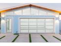 Modern home garage with a glass door and clerestory windows, set against a sleek concrete driveway with grass accents at 8308 E Mariposa Dr, Scottsdale, AZ 85251