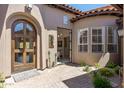 Inviting front entrance features a wooden door, a stone courtyard and lush desert landscaping at 8974 E Rusty Spur Pl, Scottsdale, AZ 85255