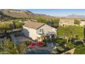 Aerial view of a home's backyard featuring a pool, patio, and lush green lawn set against a mountain backdrop at 9517 E Minton St, Mesa, AZ 85207