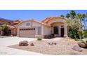 Attractive desert home with a terracotta roof, a two-car garage, and desert landscaping with native plants at 10952 S Desert Lake Dr, Goodyear, AZ 85338