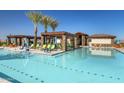 Resort-style pool area with comfortable lounge chairs, shaded cabanas, and palm trees, perfect for relaxation at 17383 W Fallen Leaf Ln, Surprise, AZ 85387