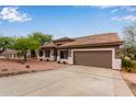 Charming single-story home featuring a well-manicured yard and a two-car garage with brown door at 18 E Paint Your Wagon Trl, Phoenix, AZ 85085