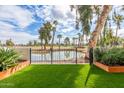 Scenic backyard view overlooking a serene pond, complemented by lush landscaping and a black wrought iron fence at 2537 N Miller Rd, Scottsdale, AZ 85257