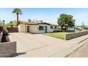 Attractive single-story home featuring a lush green lawn, a covered carport, and a welcoming front yard at 653 W Inglewood St, Mesa, AZ 85201