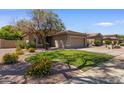 Well-maintained single-story home with lush landscaping, green lawn, and a two-car garage on a sunny day at 8237 W Alex Ave, Peoria, AZ 85382