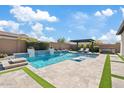 Inviting pool with a baja step, water feature, pergola with lounge chairs, and a hot tub at 10520 E Thorite Cir, Mesa, AZ 85212