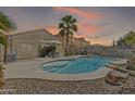 A beautiful backyard featuring a sparkling pool, patio seating, and lush desert landscaping at 40061 W Novak Ln, Maricopa, AZ 85138