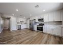Spacious kitchen with stainless steel appliances, white cabinets, and wood flooring at 5336 W Lewis Ave, Phoenix, AZ 85035