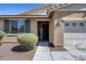 Welcoming front entrance with a covered porch, desert landscaping, and view of the two-car garage at 7634 W Redbird Rd, Peoria, AZ 85383