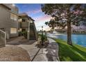 Beautiful exterior view of condo with inviting walkway, green grass, and stunning waterfront views with fountain feature at 1825 W Ray Rd # 2111, Chandler, AZ 85224