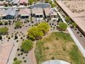 Aerial view of new construction homes surrounding landscaped greenbelt with trees and shrubs at 21090 N 267Th Dr, Buckeye, AZ 85396