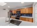 Modern kitchen with stainless steel appliances, quartz countertops, tile backsplash, and wood cabinets at 2327 E Pebble Beach Dr, Tempe, AZ 85282