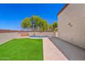 Spacious backyard featuring an in-ground pool and lush artificial grass at 2454 W Camp River Rd, Queen Creek, AZ 85144