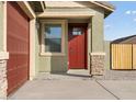 Inviting home entrance featuring a red front door, stone accents, and a covered porch, with a view of the garage at 2668 E San Miguel Dr, Casa Grande, AZ 85194